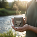Close-up of hands holding white Time by the River ceramic mug by riverside with steam rising