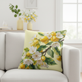Close-up of lemon blossom pillow on white sofa with yellow vases and citrus decor