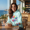 Confident woman in turquoise hearts hoodie in chic coastal city cafe