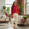 Cream wide-leg track pants with red geometric pattern styled with red hoodie in plant-filled Scandinavian interior