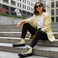 Stylish woman in black jeans white tee and yellow blazer with geometric high-top canvas shoes