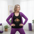 Woman in black Journey of Life tank top with purple hoodie and athletic leggings in fitness interior