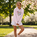 Woman in pink hearts hoodie with white tennis skirt outdoors