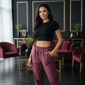 Woman wearing burgundy track pants with black jaguar design and black top in luxurious interior with gold accents